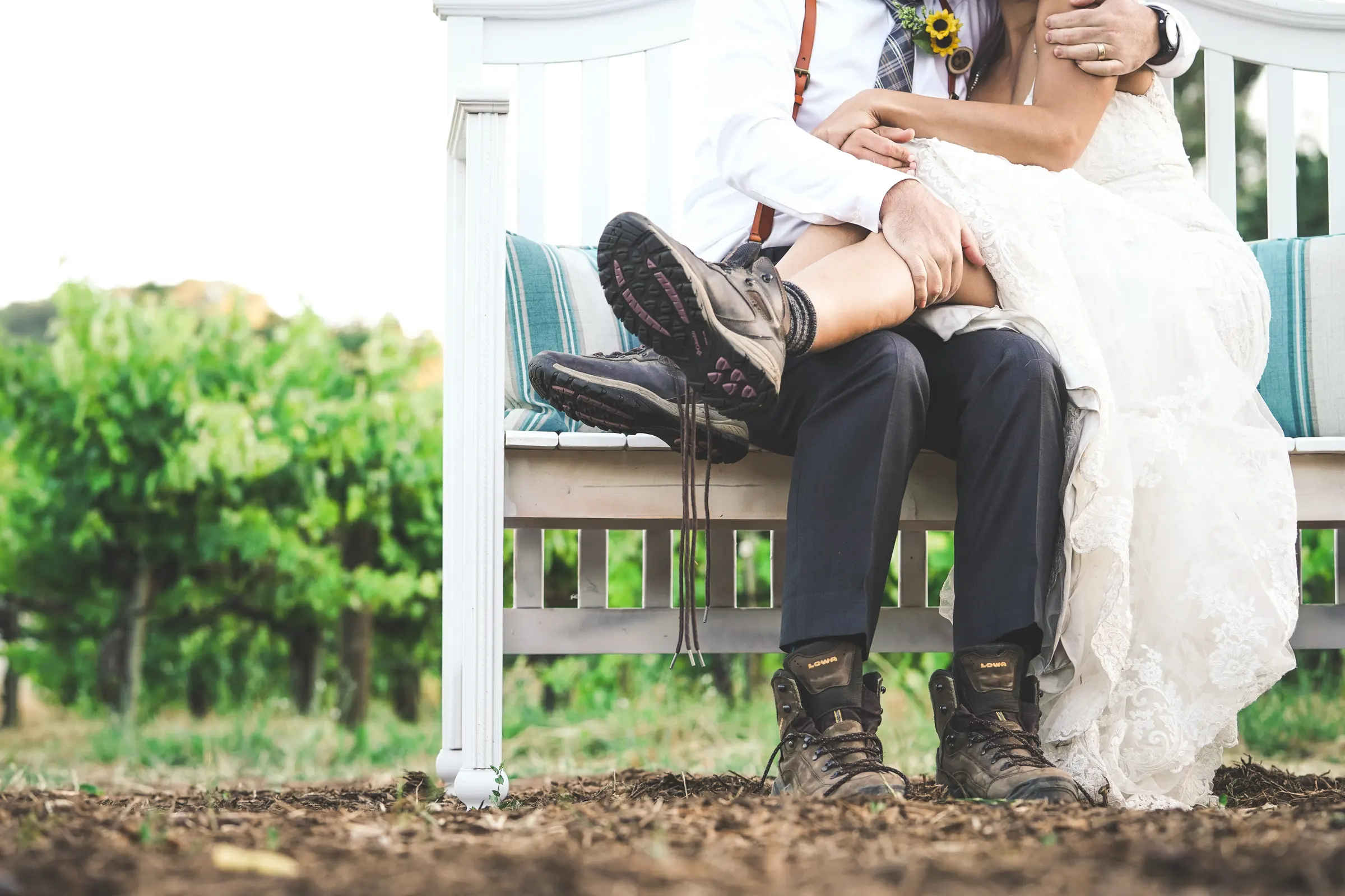 A newly married couple sitting together on a bench beside the vines